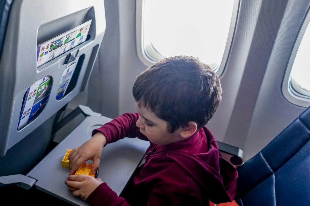 A boy playing with toys in his plane seat